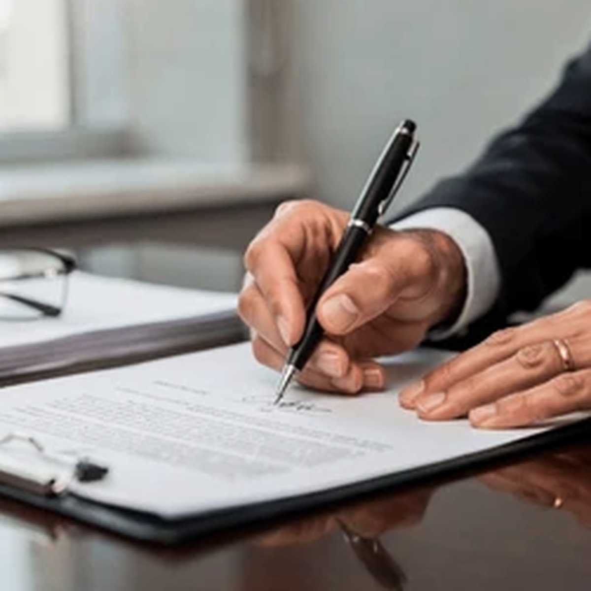 Hands signing a formal document